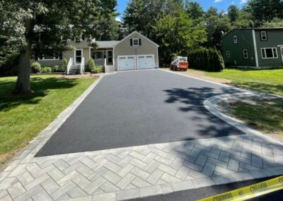 New asphalt driveway installation with elegant paver apron and border, showcasing home improvement in Tewksbury, MA