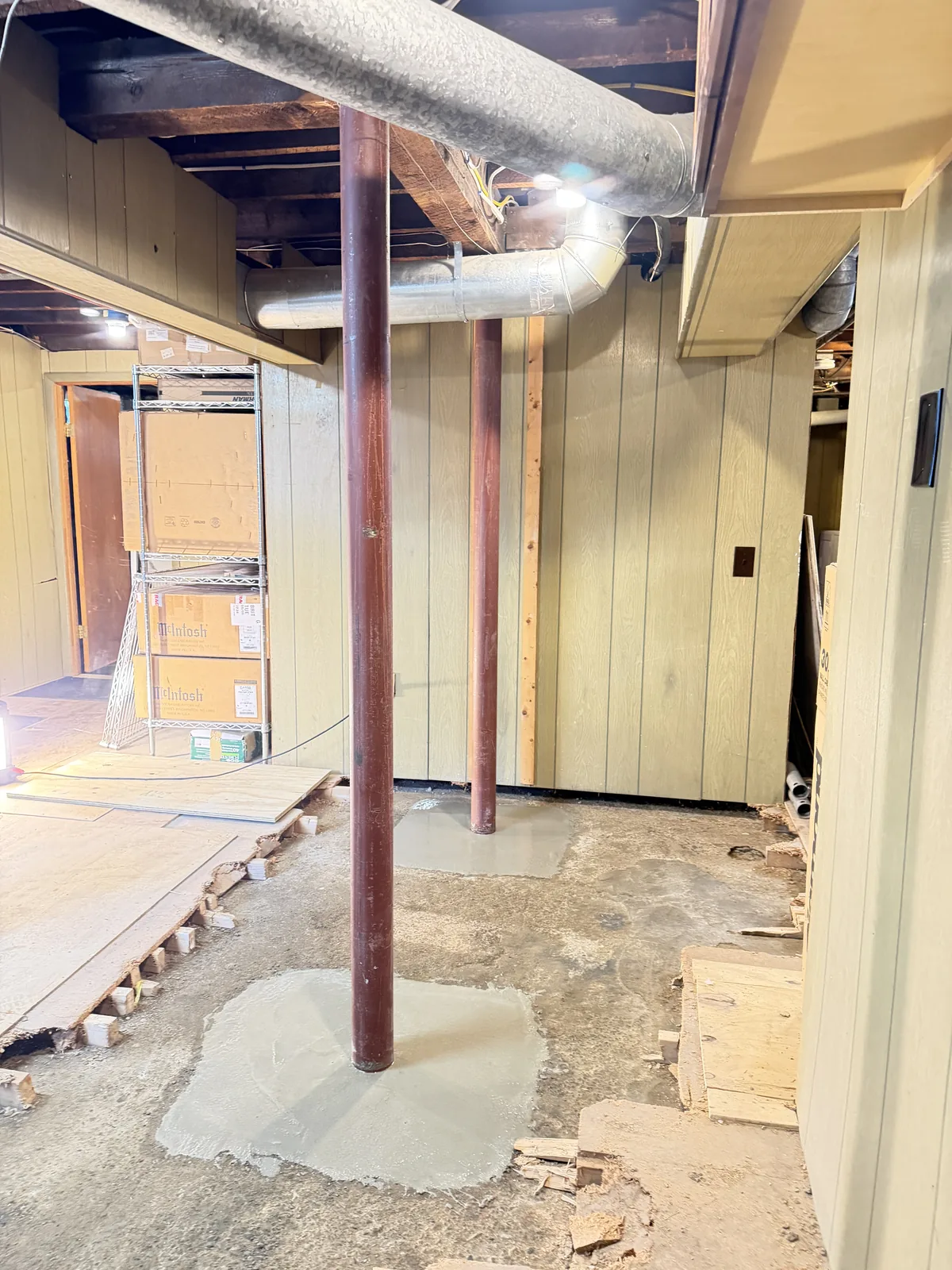 Installed steel basement columns with fresh concrete patches at their bases