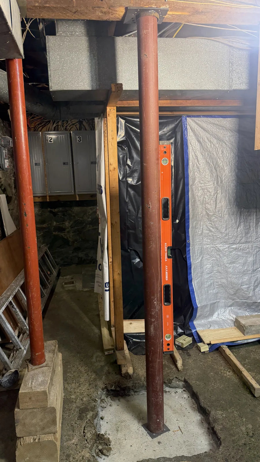 New steel Lally column with a level alongside it during installation